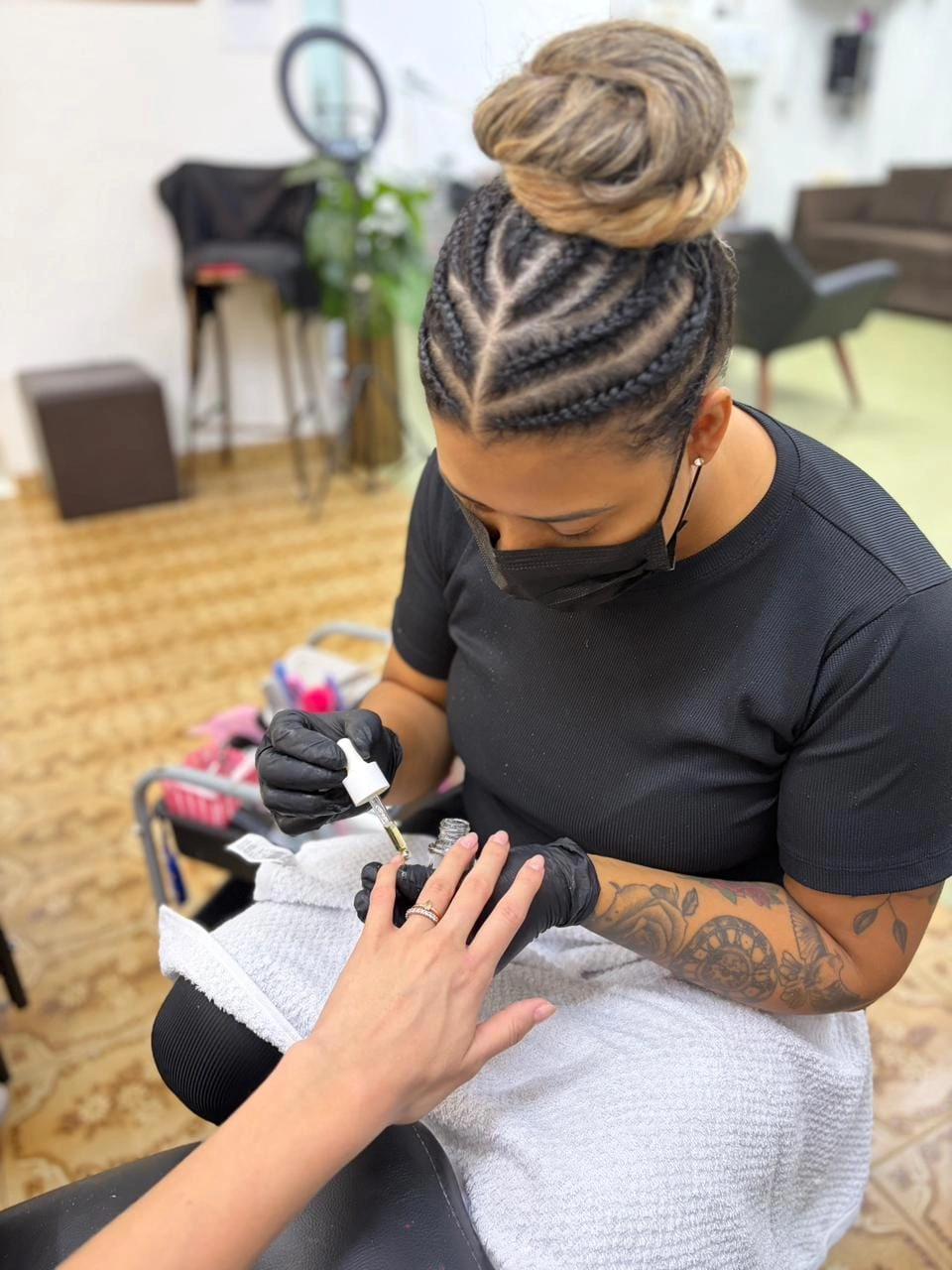 Manicure trabalhando delicadamente nas unhas de uma cliente no estúdio